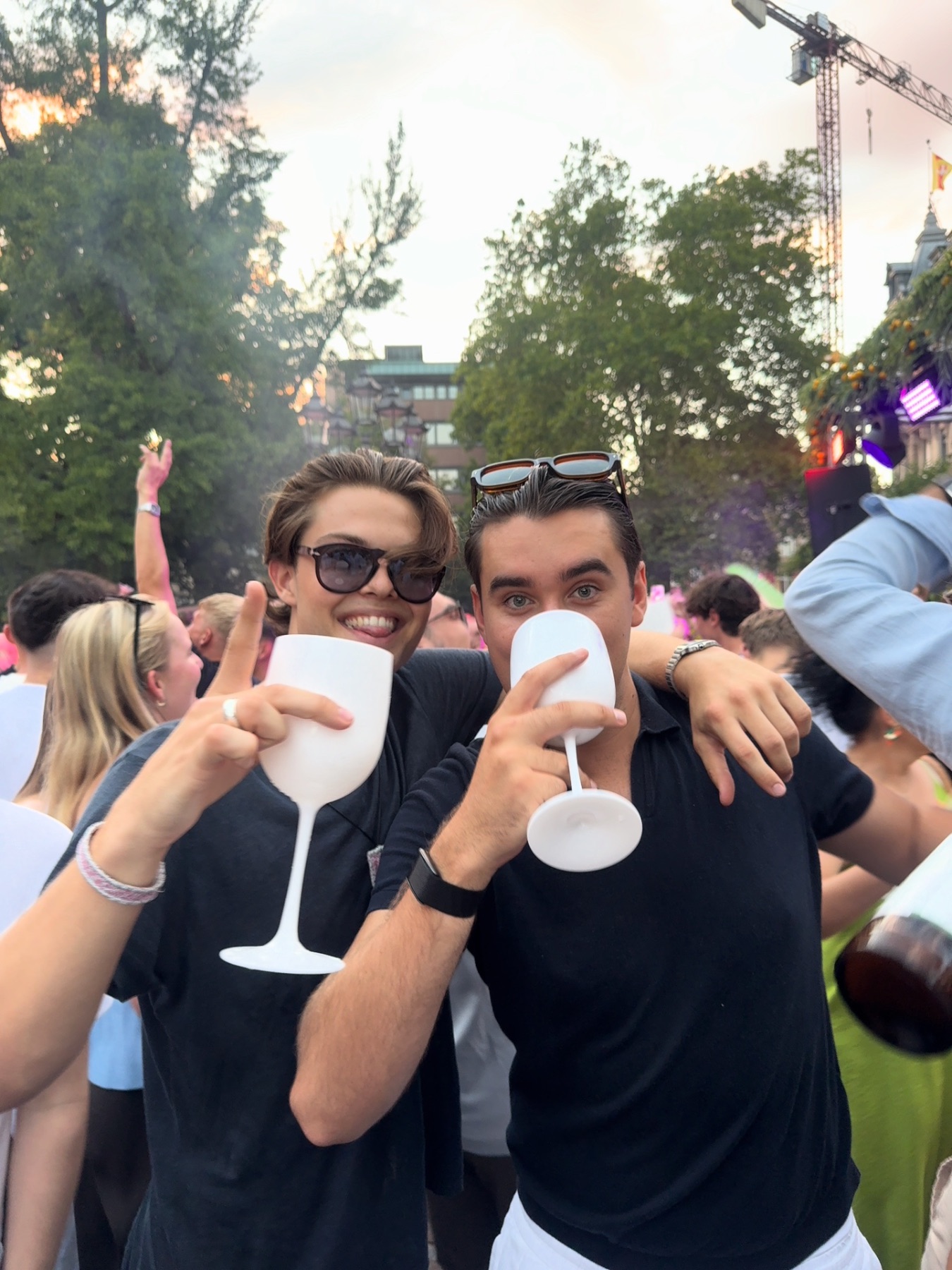 Zwei Gäste stoßen bei einem Open-Air-Event mit weißen Gläsern an